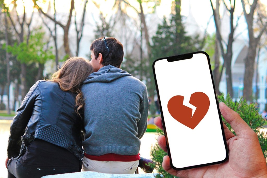 image of phone with a broken heart with a man and woman with their backs facing the person holding the phone
